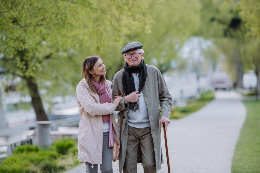 Old man walking happily with support of younger woman