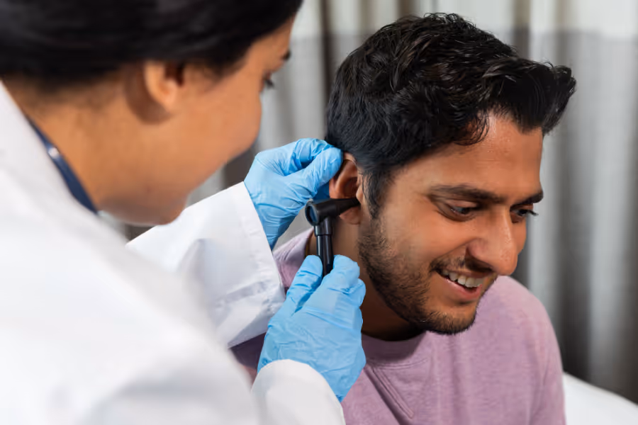 ENT surgeon examining young male patient's ear