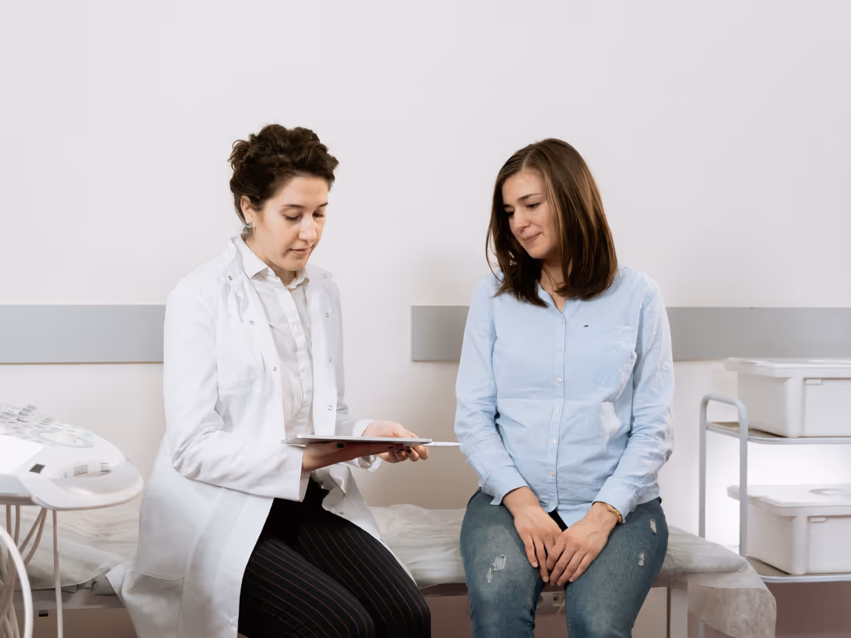 Private gynecological surgeon consulting with prospective female patient on medical table