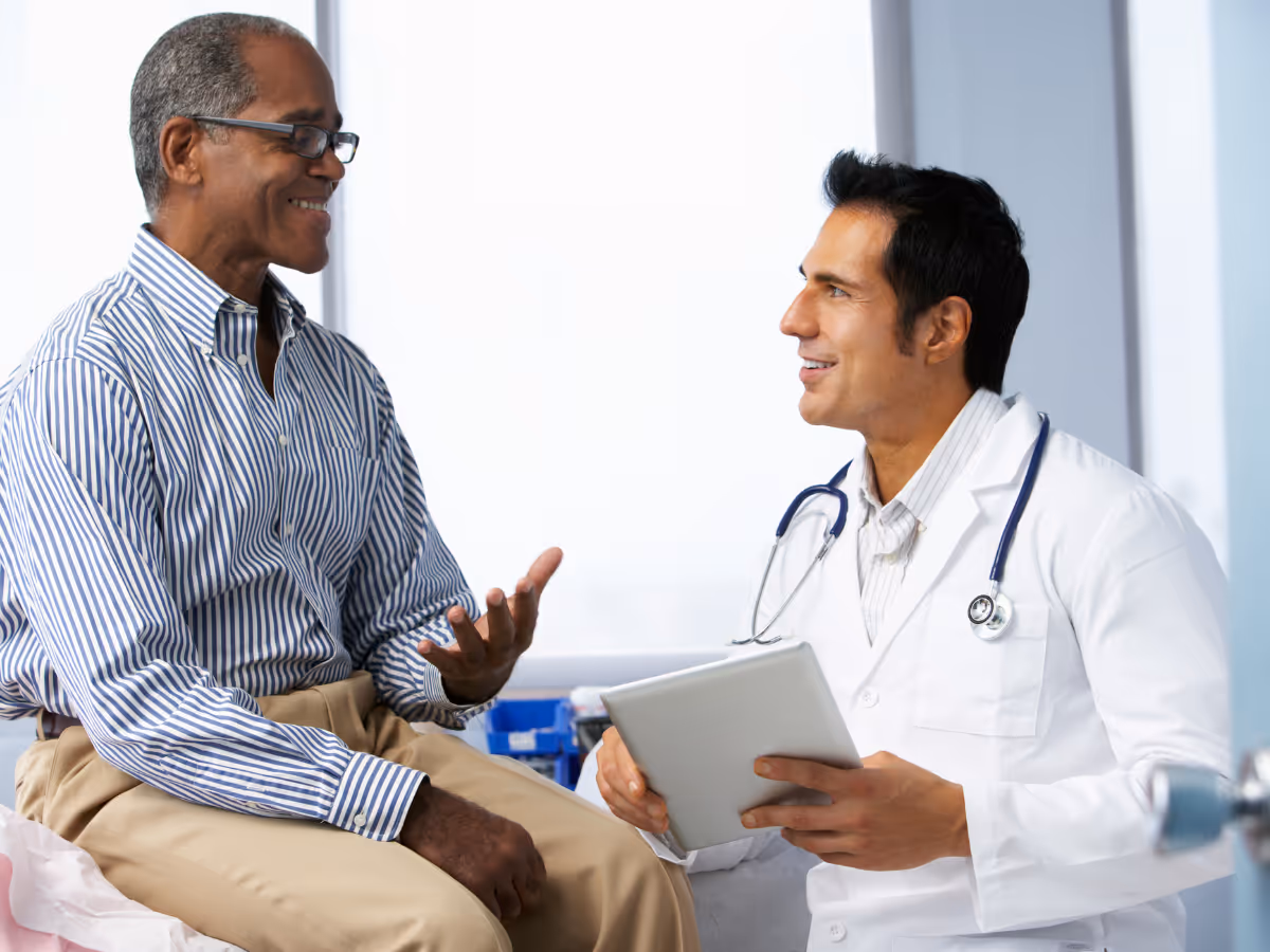 Private colorectal surgeon consulting with older male patient on surgical table