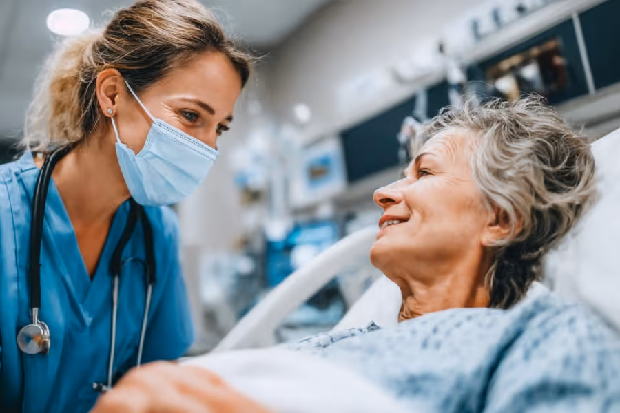 Older patient on a surgery table post-surgery, speaking with a female nurse
