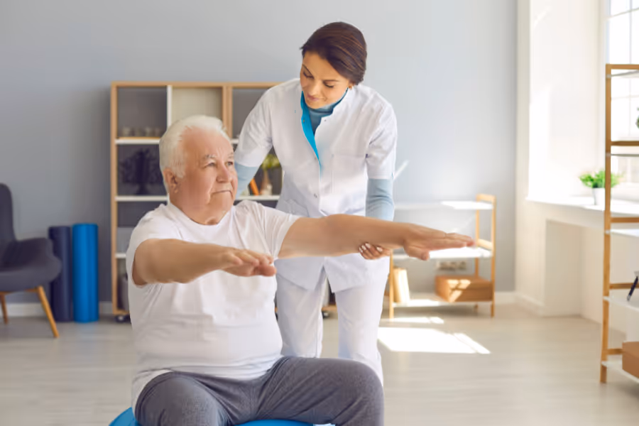 Older male patient applying himself to rehab post hip replacement surgery with the help of a physiotherapist