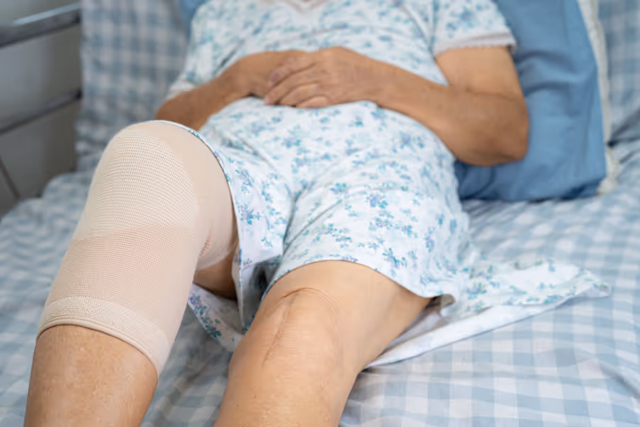Patient in bed with a fresh wrap for knee post-surgery