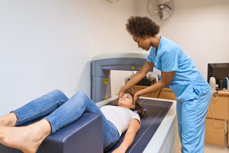 Un clinicien assiste une patiente lors d'un examen DEXA.