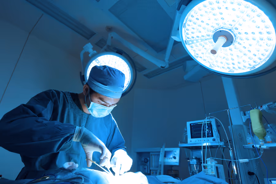 Private general surgeon operating on fistulae excision in operating room.