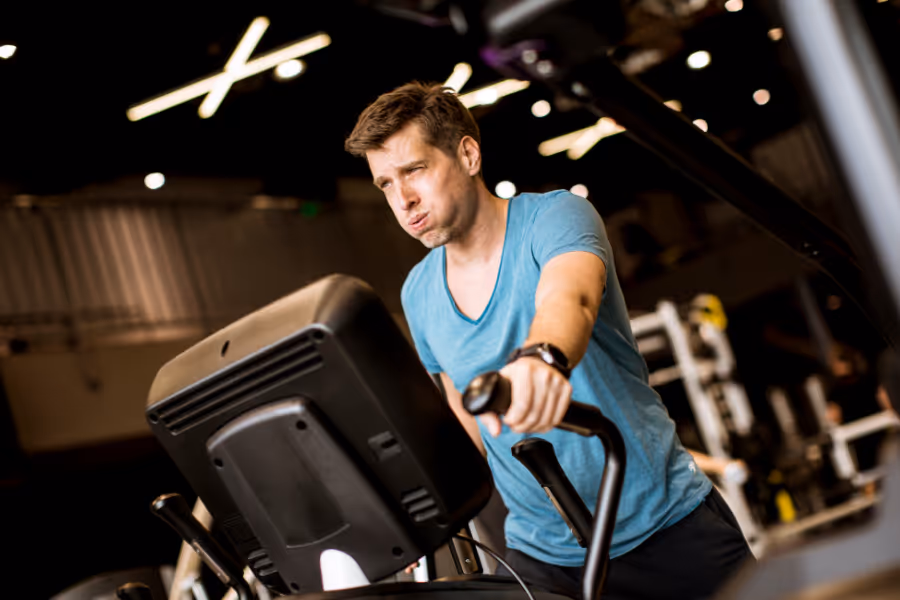 Man huffing on an elliptical machine