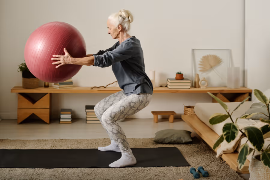 Older woman doing shallow squat with bosu ball for counter leverage