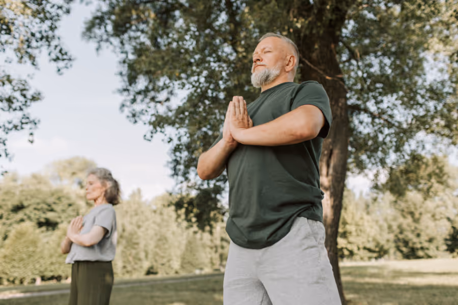 Man and woman doing yoga in the sunny park after hip replacement recovery