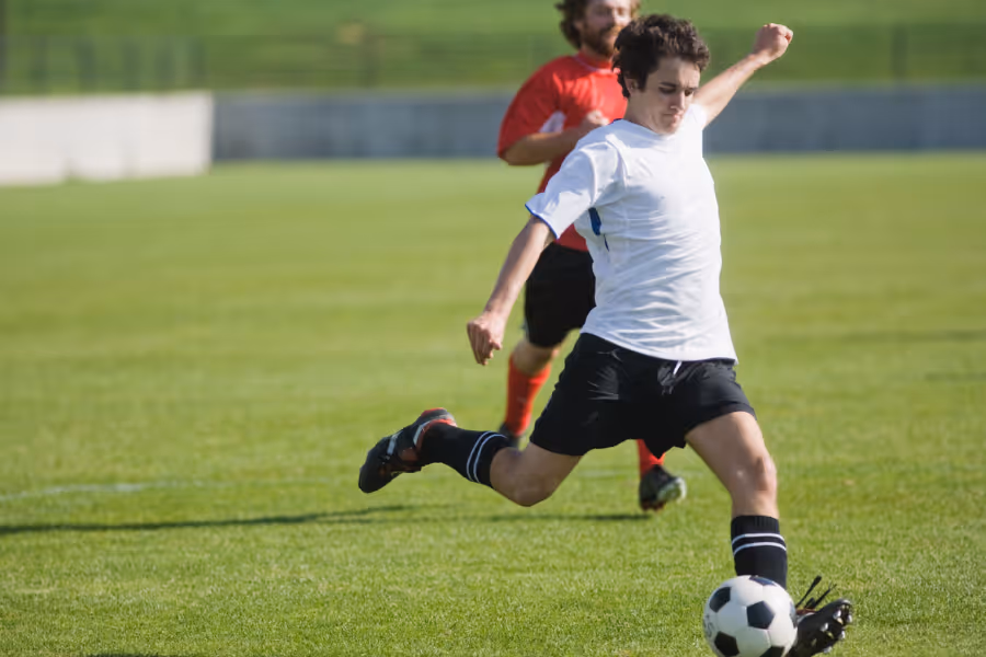 Young man playing soccer on green field
