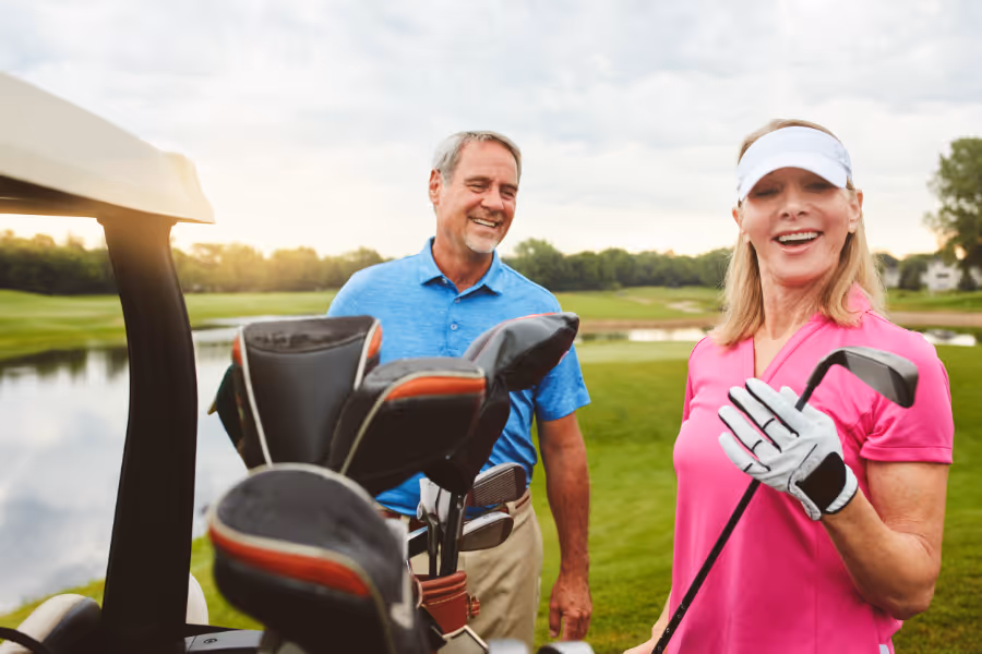 Un couple âgé sur un terrain de golf ensoleillé, souriant
