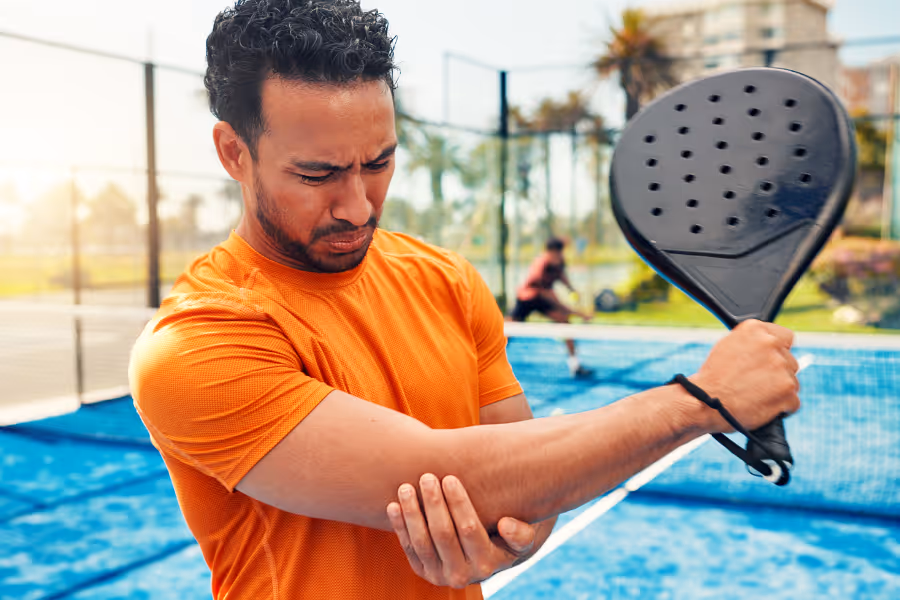 Un joueur de pickleball masculin se frotte le coude endolori