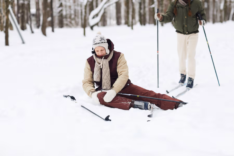 Teenage girl holding her knee in pain on snow covered ski slope
