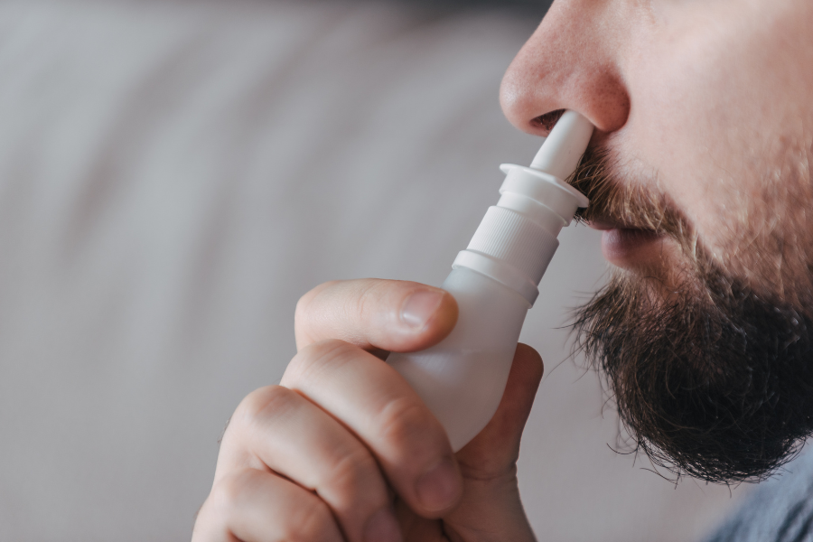 Man using saline spray on nose