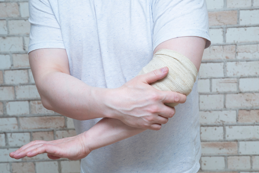 Muscular male holding elbow in pain