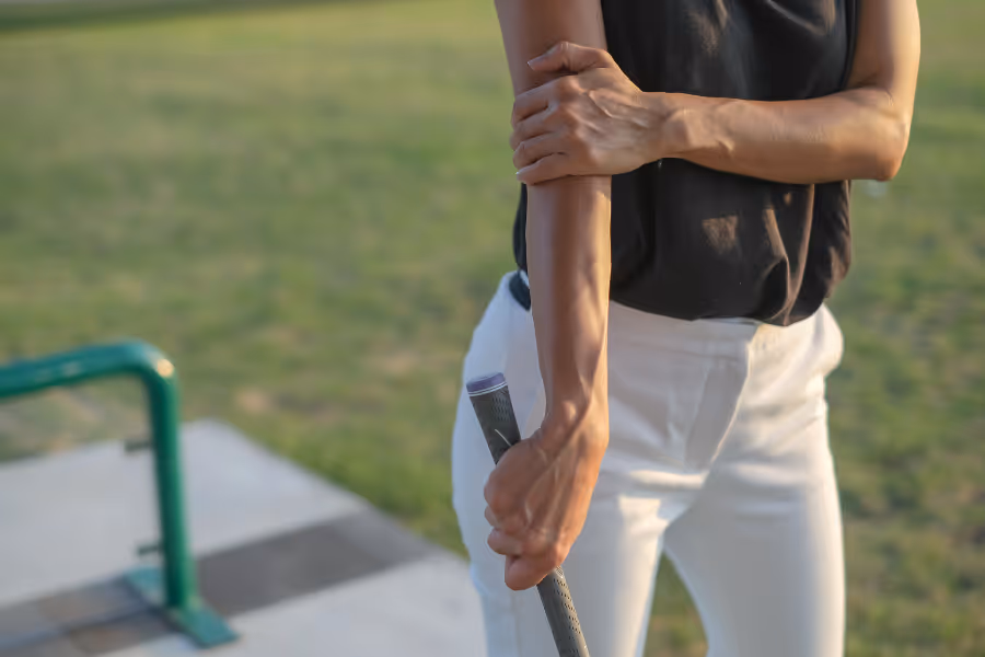 Female golfer experiencing tennis elbow pain