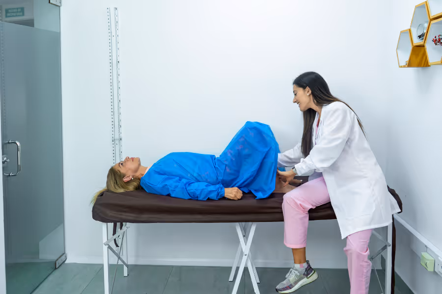 Chirurgienne inspectant le plancher pelvien d’une patiente sur la table médicale