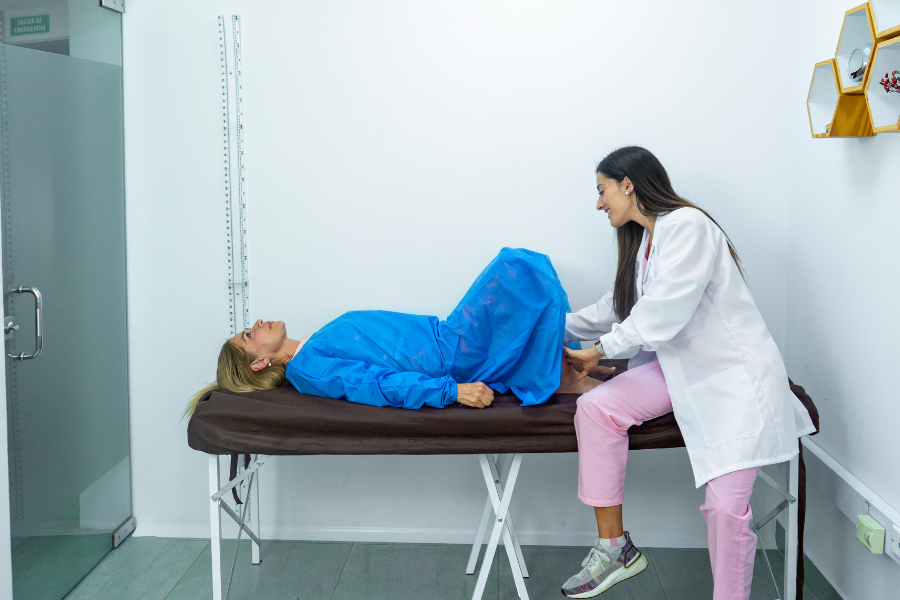 Female surgeon inspecting female patient's pelvic floor on medical table