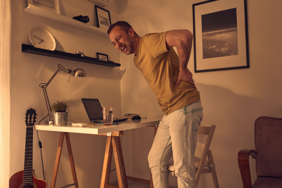 Middle aged man in visible pain from sports hernia at his work desk