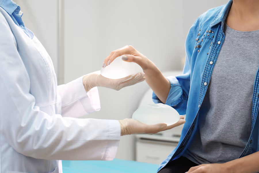 Female patient selecting the implant for breast augmentation surgery in surgeon's office