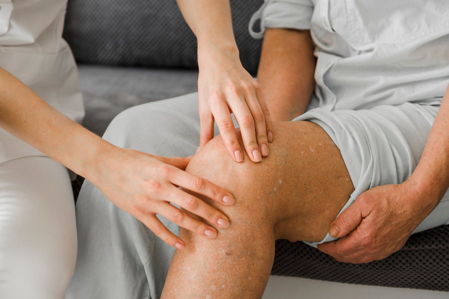 Female nurse examining an older patient's knee after ACL surgery