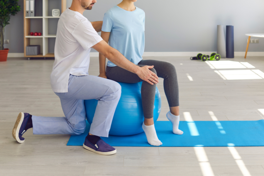 Male physio assists female patient after spine surgery