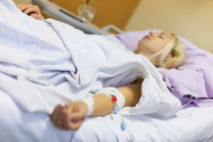 Woman recovering in medical bed immediately after hysterectomy
