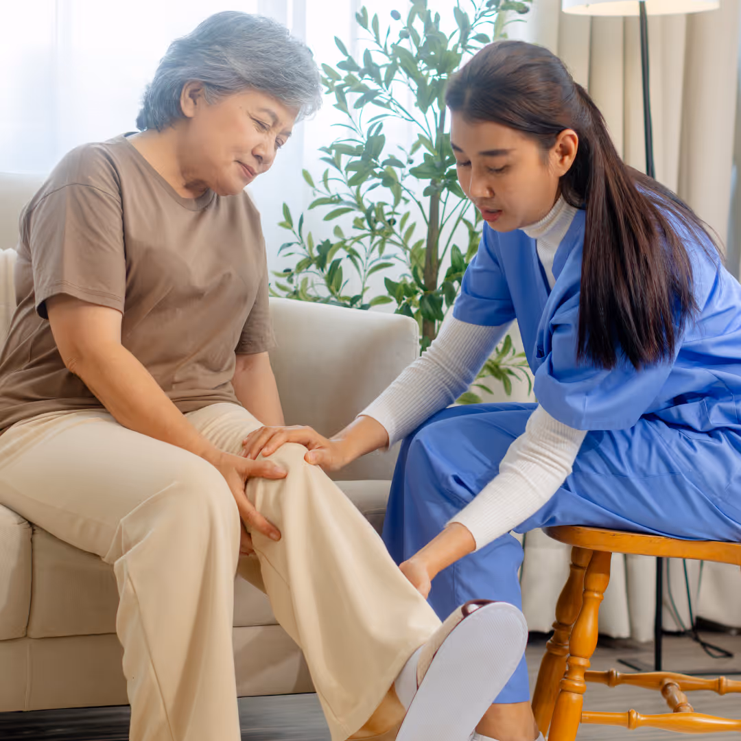 Older woman being assessed by female physician for knee pain