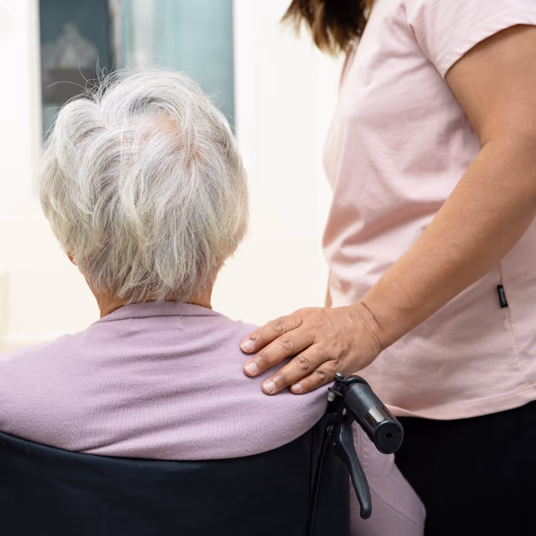 Post surgery home care assistant helping elderly woman in wheelchair after surgery