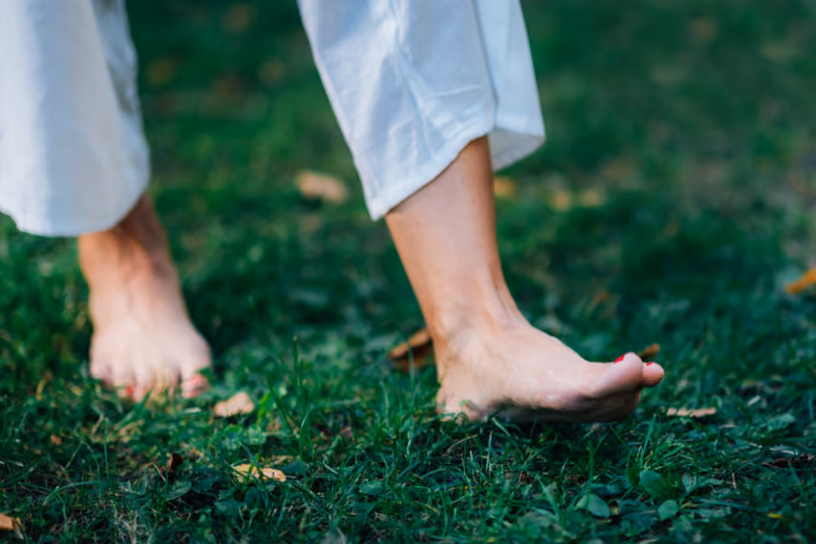 woman walking barefoot on green grass