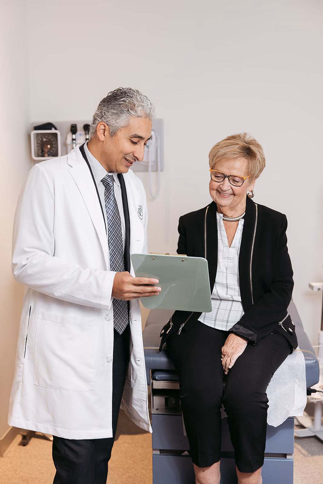Mina Morcos consulting with elderly female patient about knee replacement surgery.