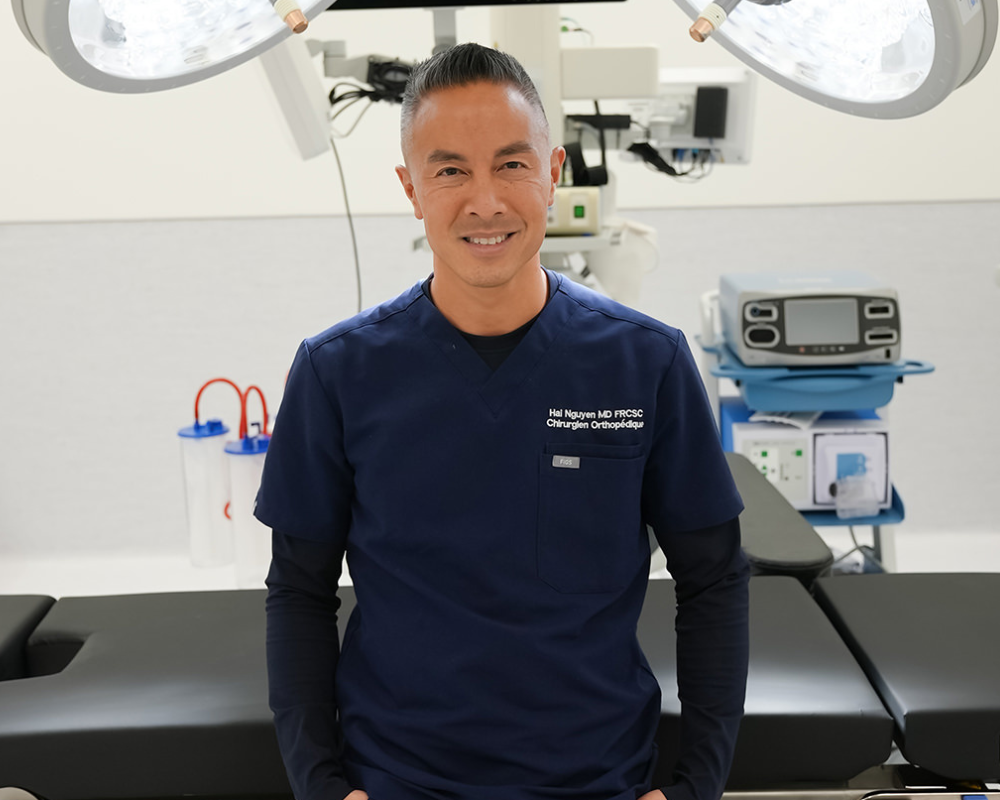 Dr. Hai Nguyen sitting on operating table in clean clinical setting.