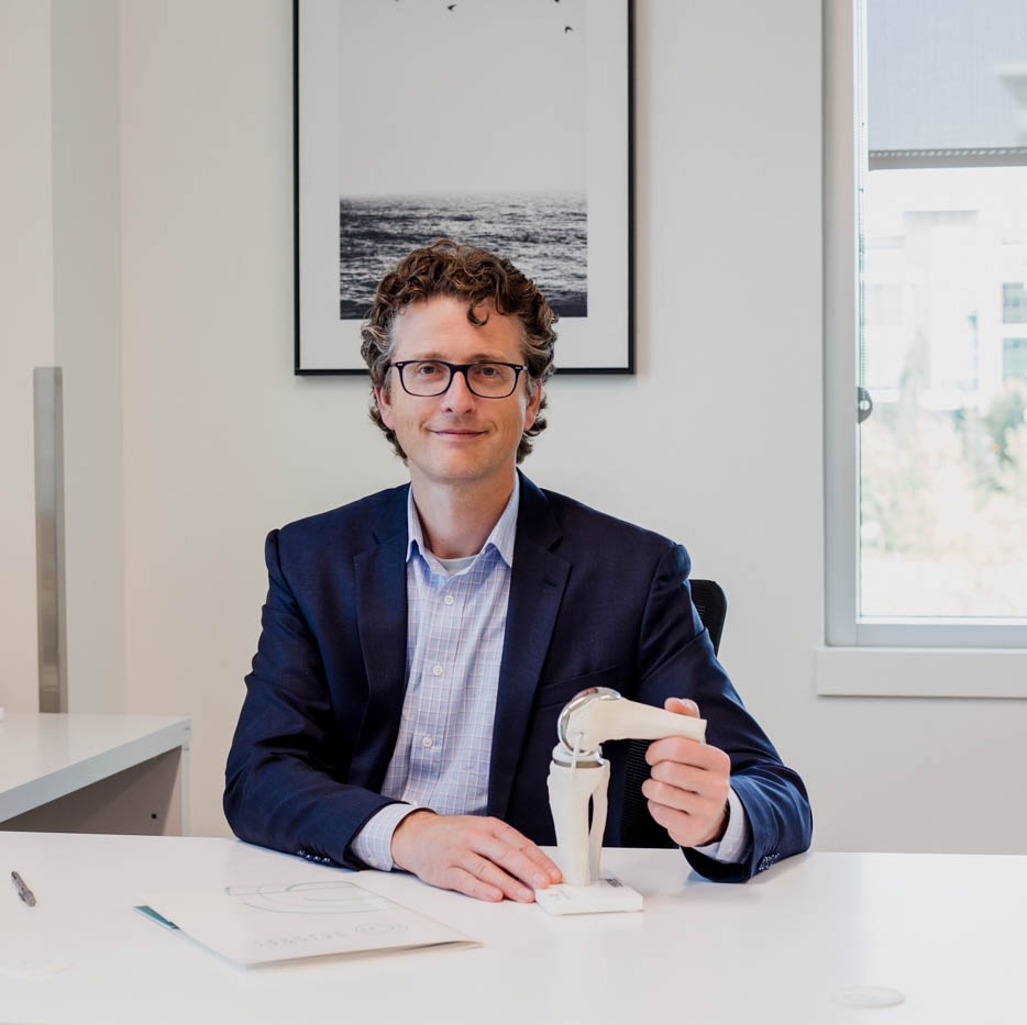 Le Dr Johnston dans son cabinet médical, tenant un schéma de l'articulation du genou