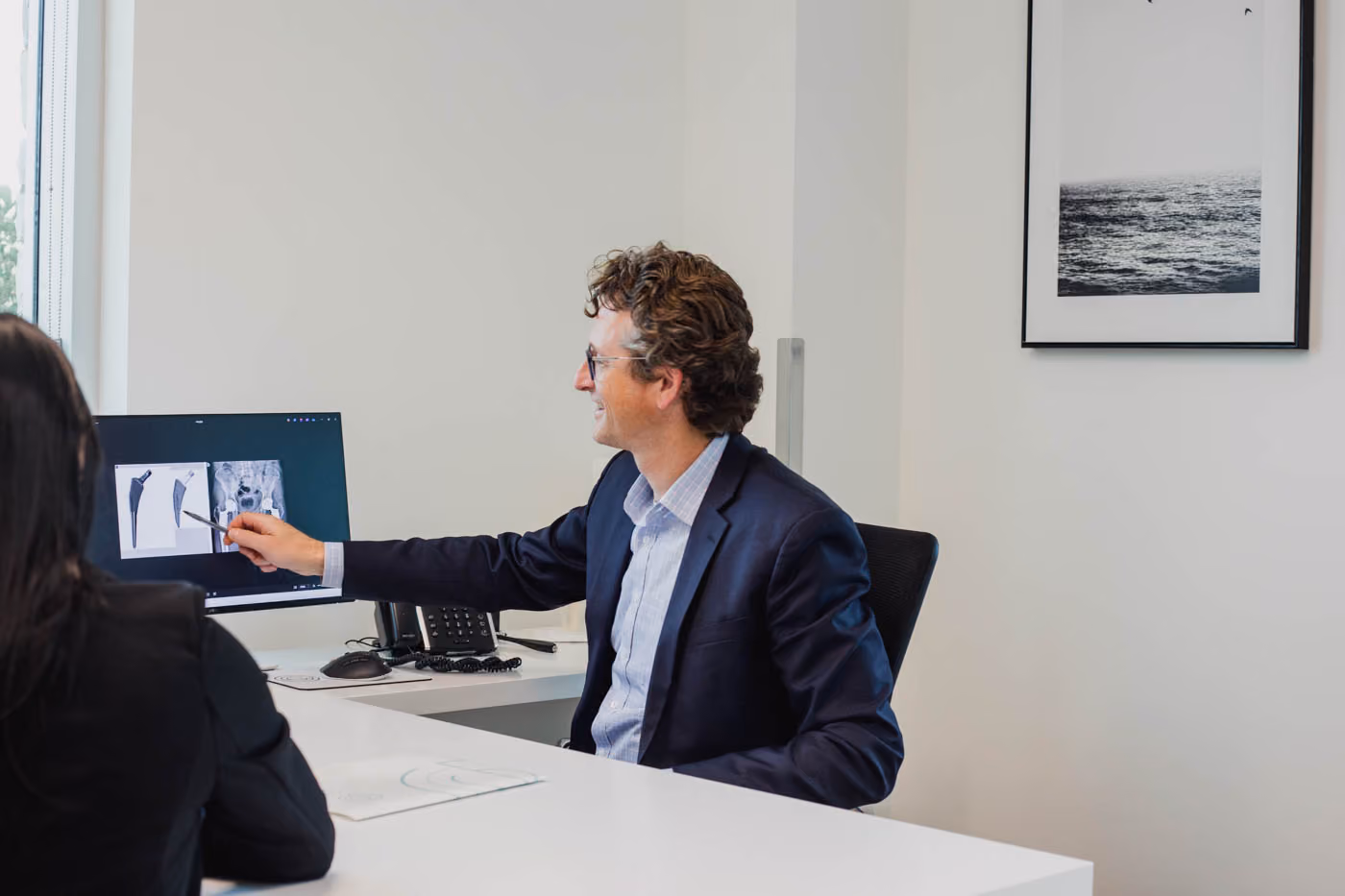 Dr. Johnston directing female patient's attention to computer screen in his office.