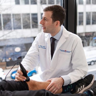 Dr Adam Hart examining patient's knee. 