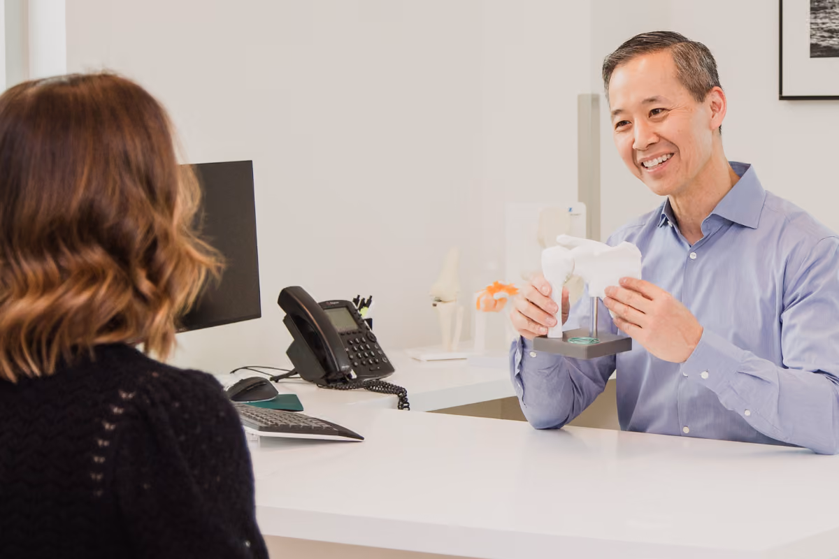 Dr. Lo showing a female patient a diagram of the shoulder joint in clinical setting.