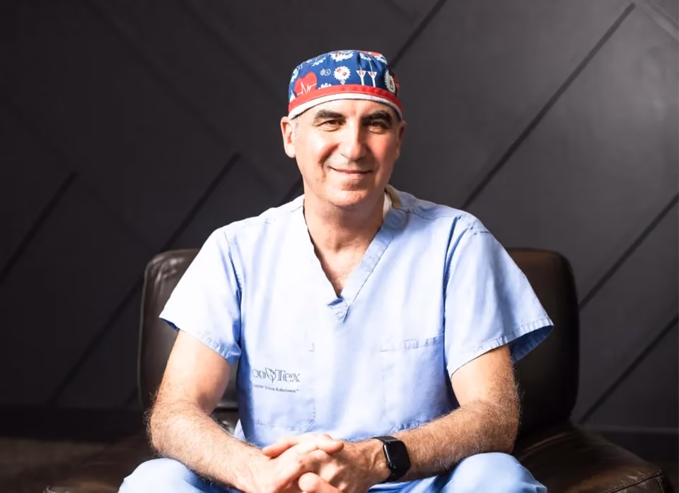 Dr. Zalzal smiling, seated on a black leather couch