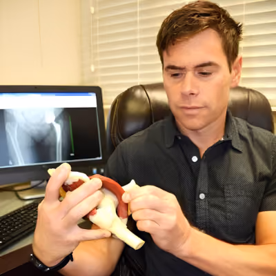 Dr. Tim Bell in his office showing a joint diagram