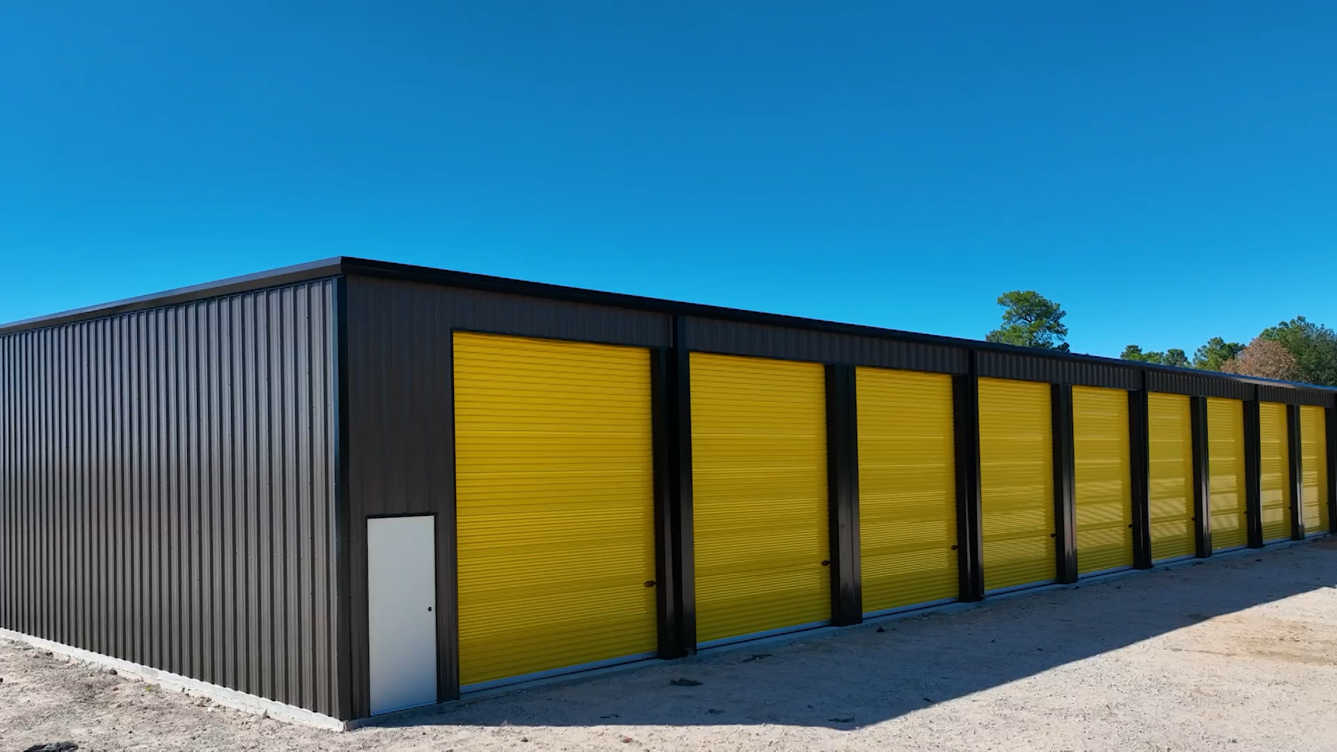 Dark grey storage building with bright yellow garage style doors.