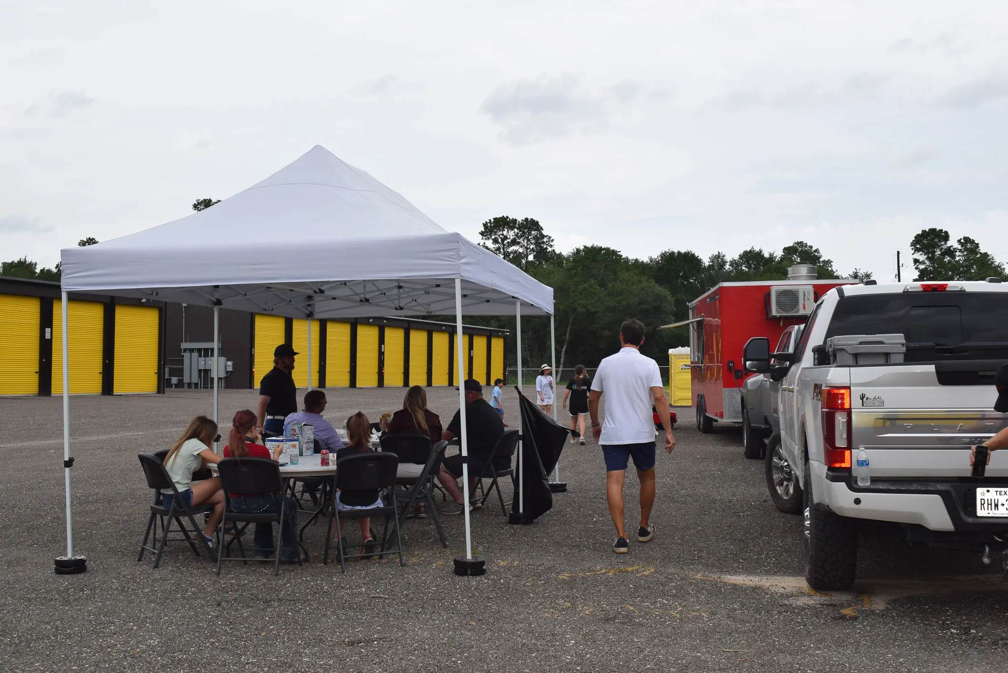A row of enclosed storage units with bright yellow roll-up doors on dark metal buildings at Foxgate Boat & RV Storage.