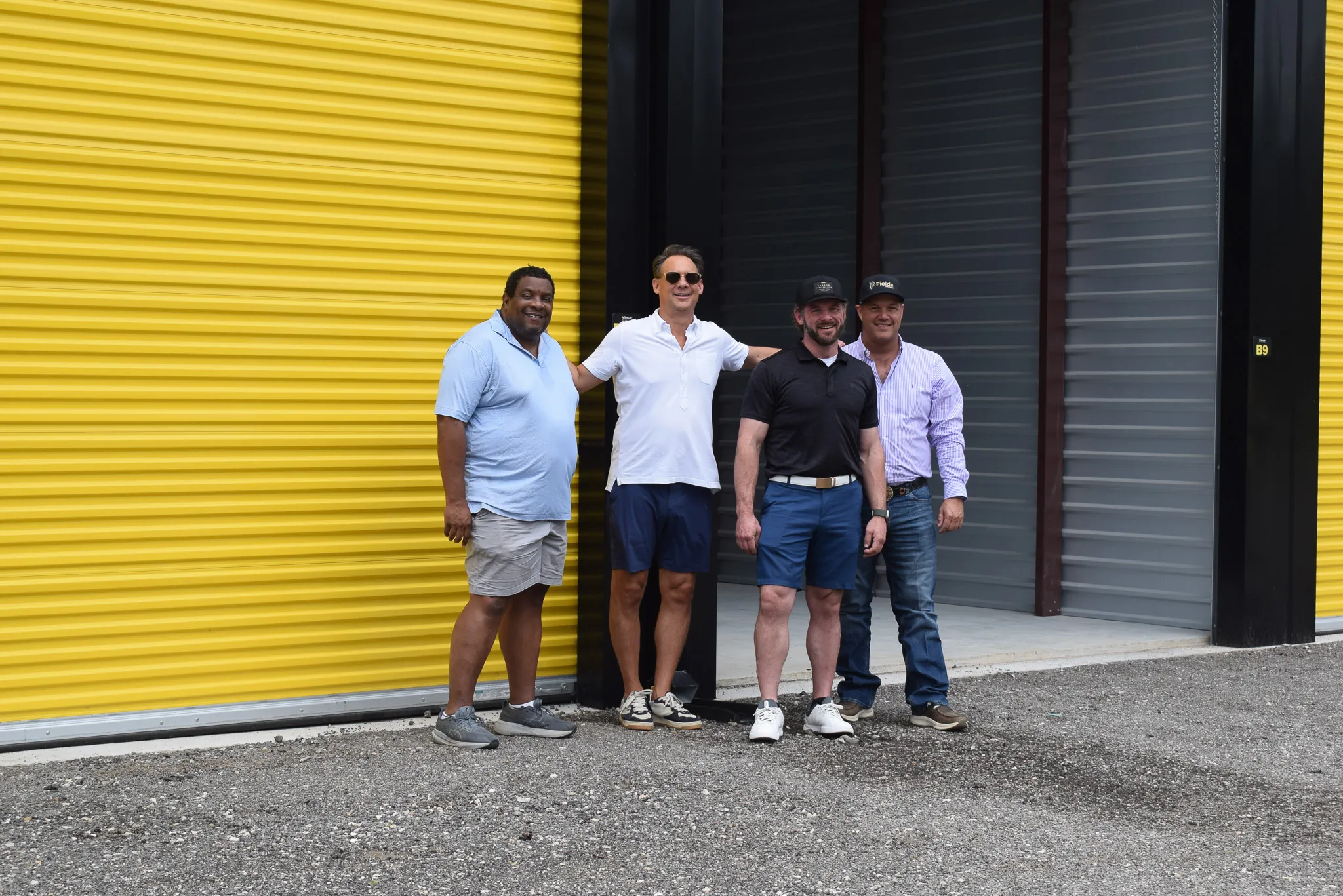 A group of people posing together in front of the yellow storage doors at the Foxgate Boat & RV Storage grand opening.
