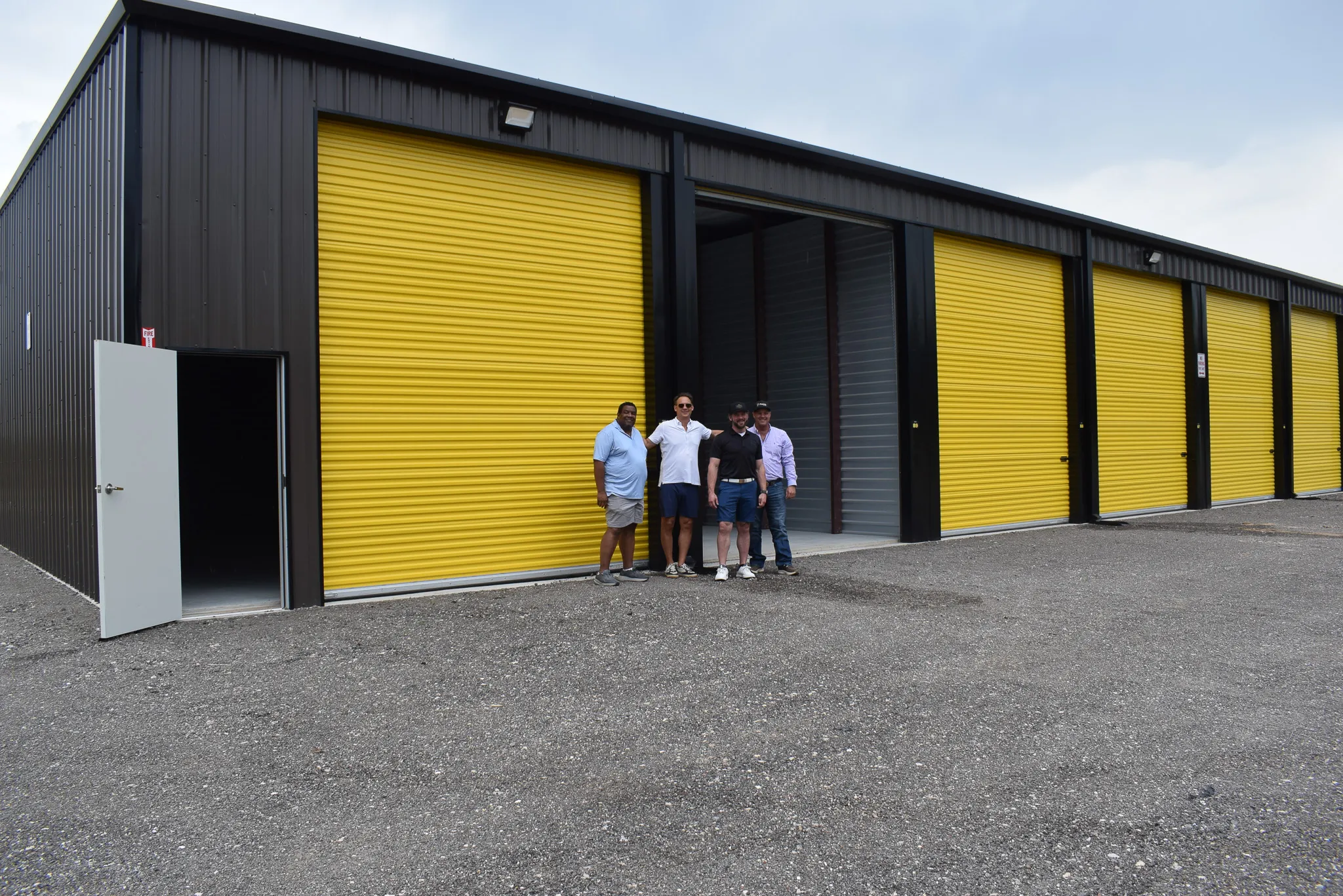 Close-up of the bright yellow roll-up doors on a dark metal Foxgate Boat & RV Storage building.