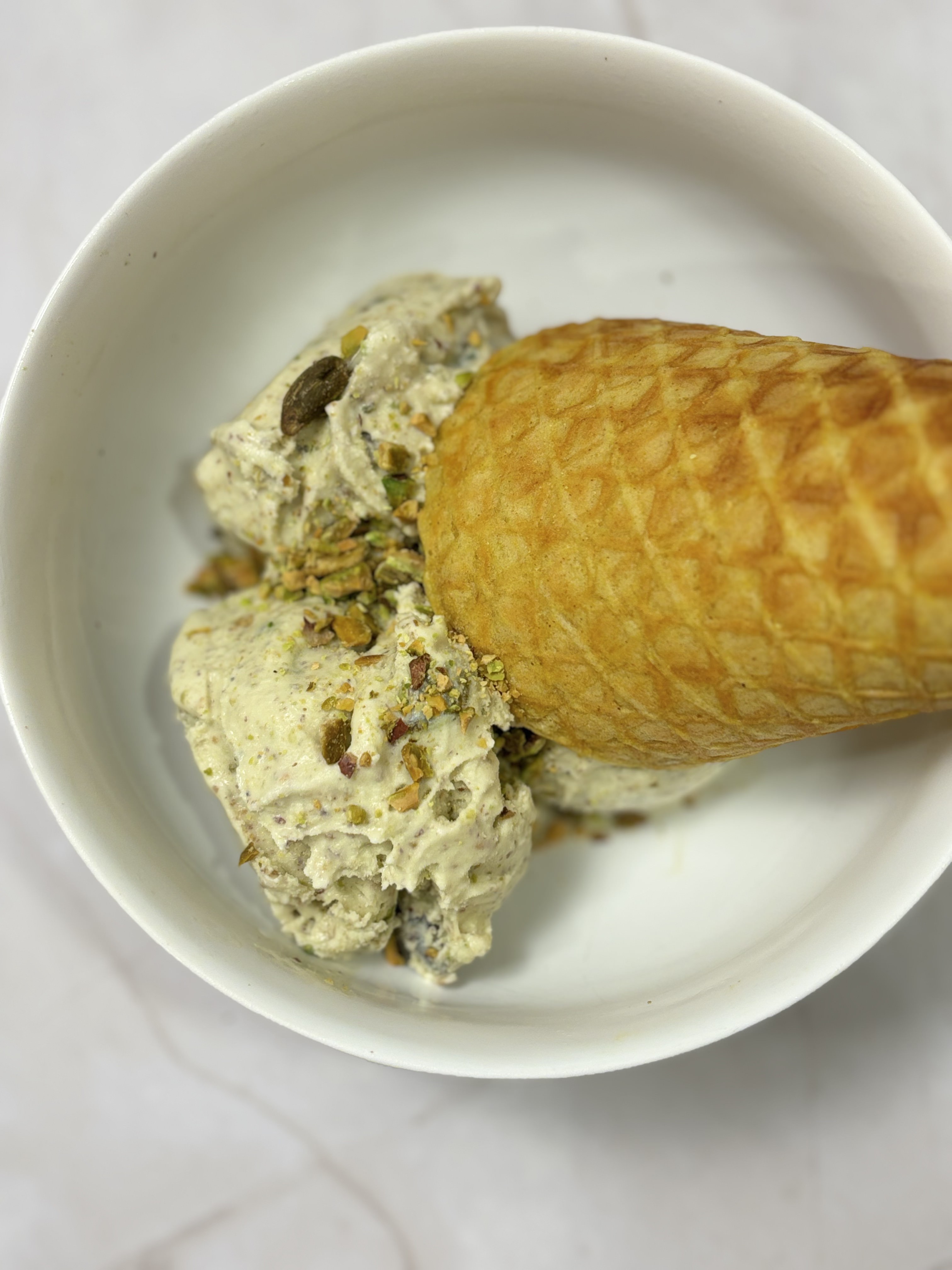 Homemade sugar-free and dairy-free pistachio ice cream in a waffle cone
