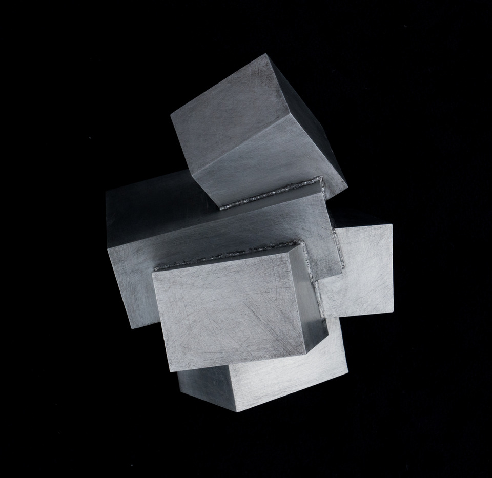 Sculpture of interlocking and unevenly stacked gray rectangular shapes and square cubes
