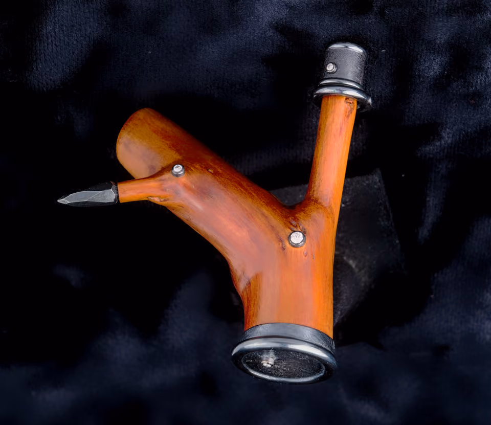 Y-shaped brooch of reddish-brown wood with ends capped in metal