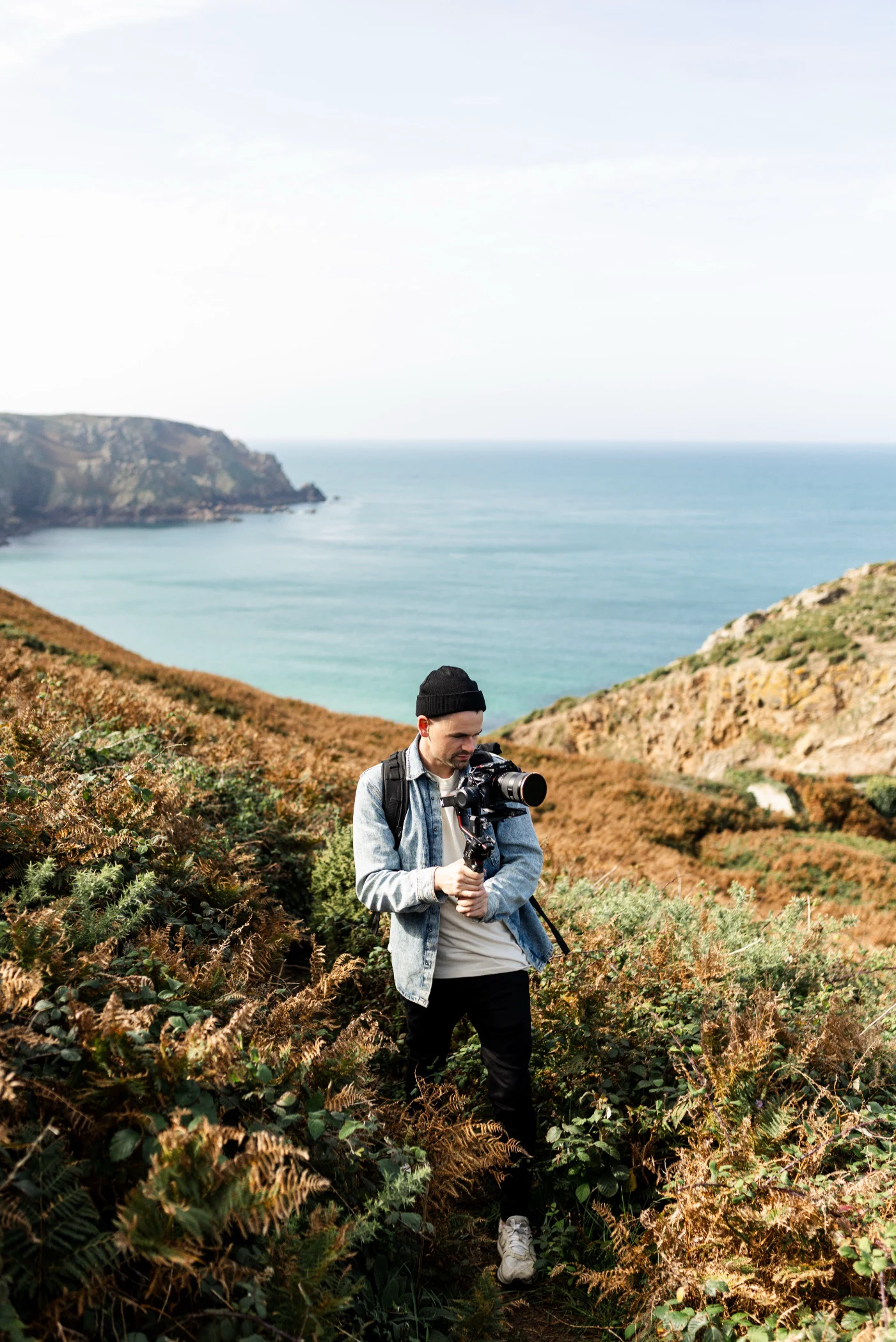 Photographer filming coastal landscape with rocky cliffs and ocean view
