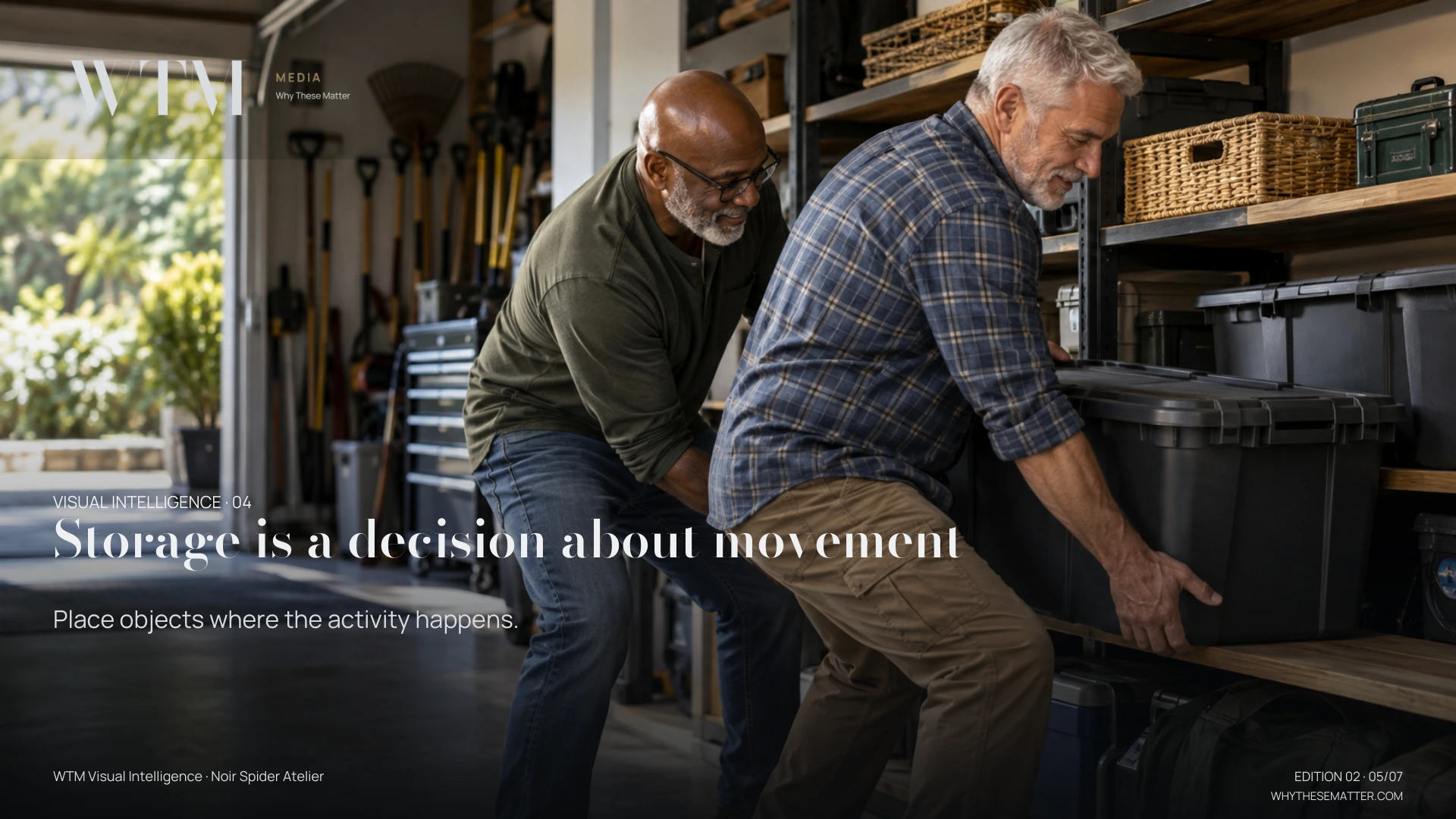 Illustrative scene: two older interracial gay husbands placing a heavy storage container onto a stable low shelf, carefully organised utility space. Decision: Place objects where the activity happens.