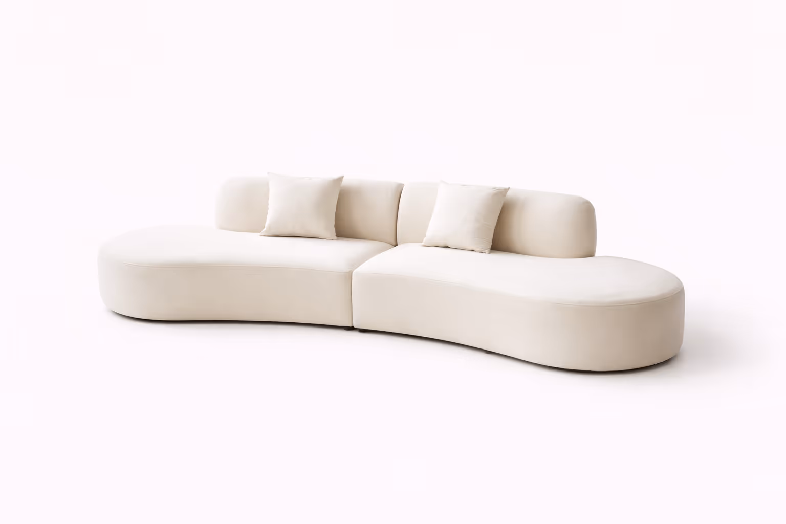 A white half-moon shaped white sofa with several pillows against a white background