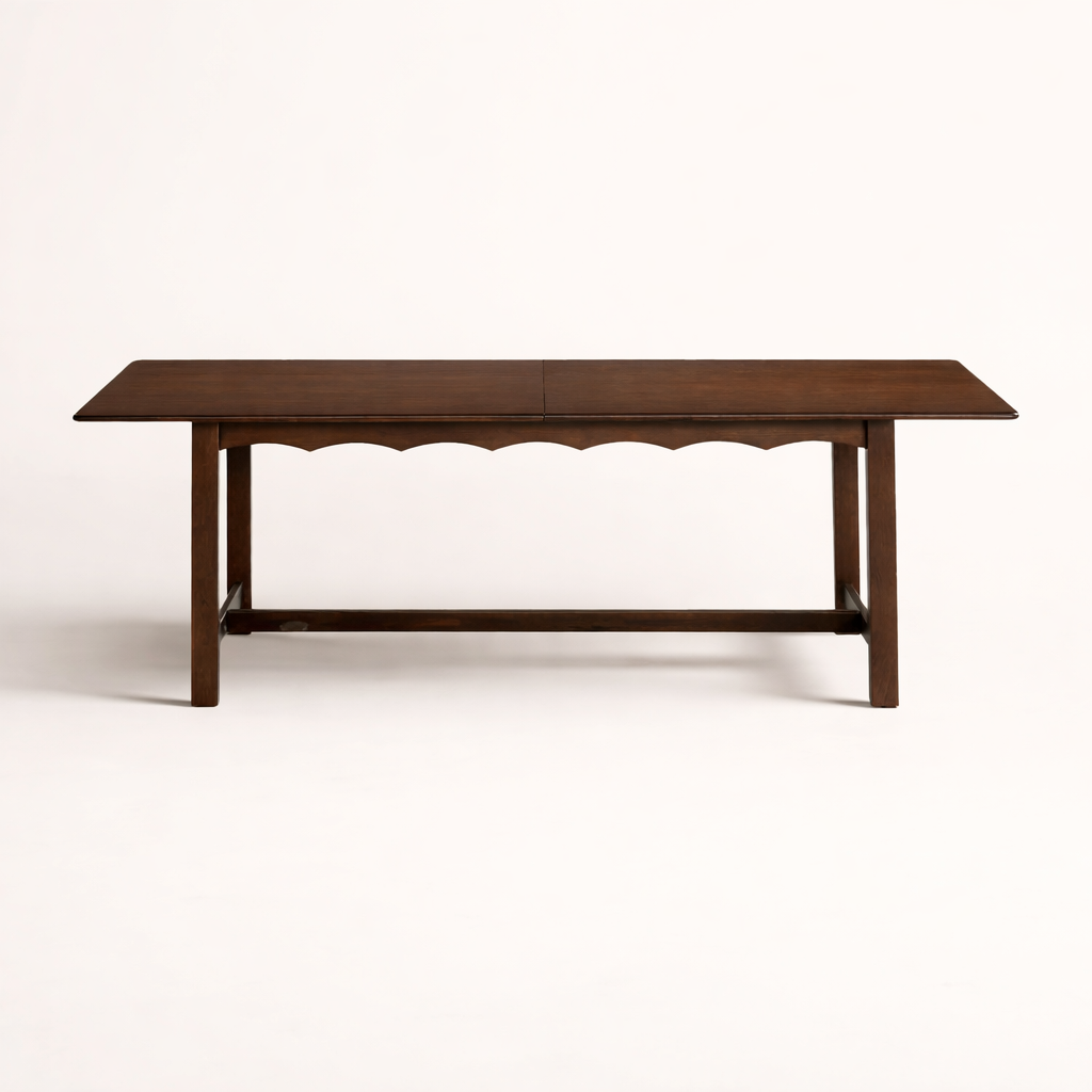A walnut dining table with scalloped edges against a white background.