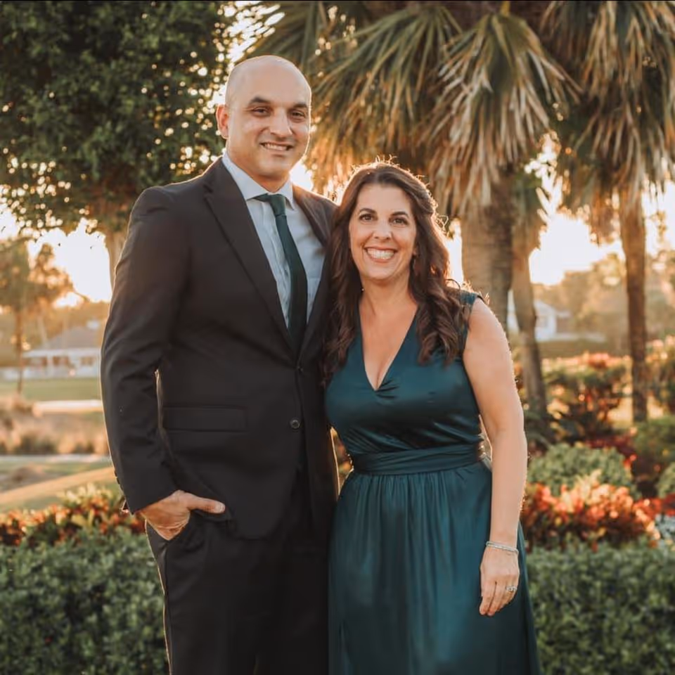Kris Torres and his wife dressed formally, smiling together outdoors at sunset
