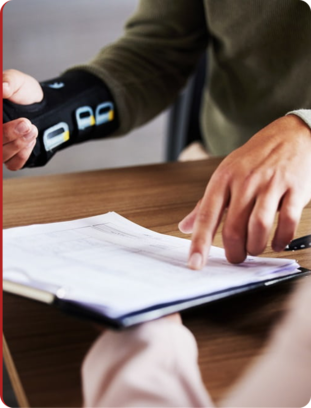 Person wearing a wrist brace pointing at documents on a clipboard during a discussion.